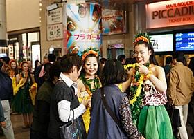 有楽町マリオンで買い物客に笑顔で レイをかけるフラガールたち「フラガール」