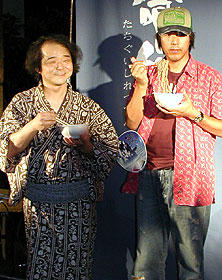 プロダクションI.G.代表・石川光久氏（右）と ソバを手に撮影に応じる押井監督