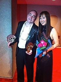 トロフィーを手に笑顔をのぞかせる クロード・ガニオン監督と工藤夕貴「カラカラ」