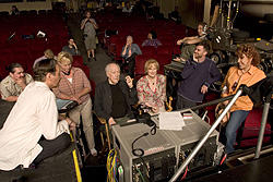 「今宵、フィッツジェラルド劇場へ」撮影現場にて キャストたちに囲まれる監督（中央）